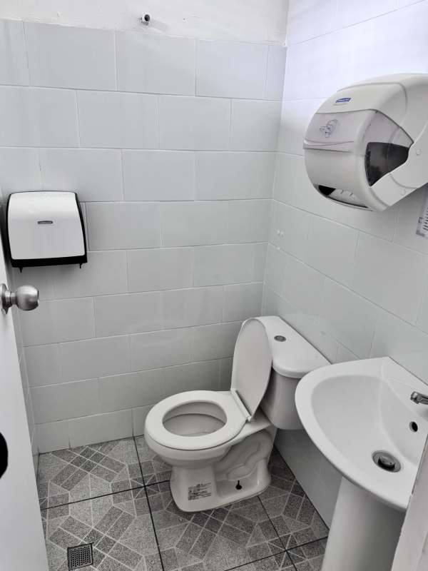 Simple bathroom interior with white tiles, toilet and sink in commercial space Panama City