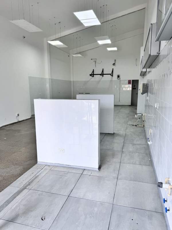 Open retail interior with gray tiled floors, white walls, and elevated platform area in Panama City