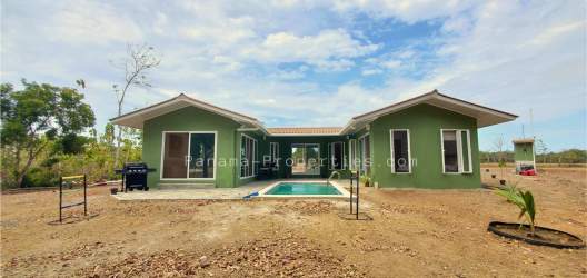 Single story green house with red roof and fenced yard near Pedasi Panama