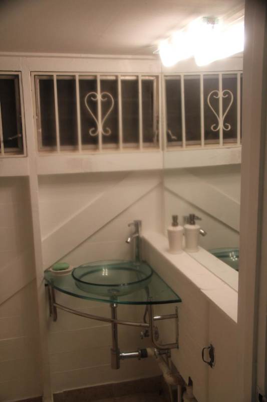 Minimalist modern bathroom with glass vessel sink and black & white accents in Ancón rental Panama City
