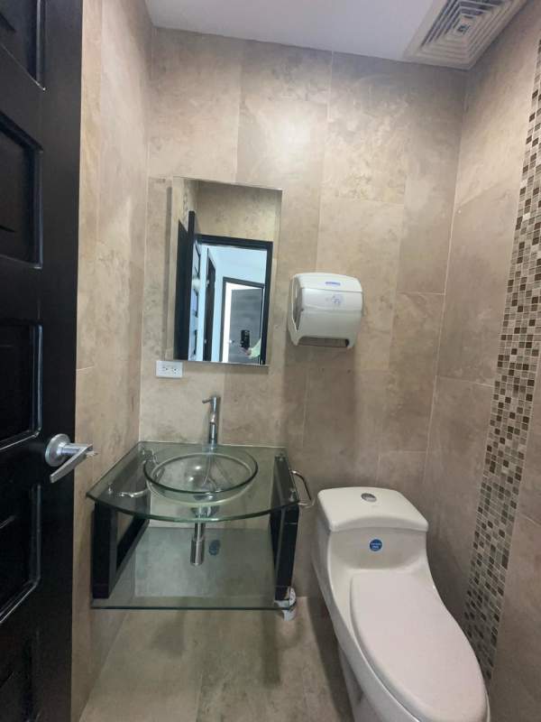 Small modern tiled bathroom with glass sink and fixtures inside F&F Tower office Panama City
