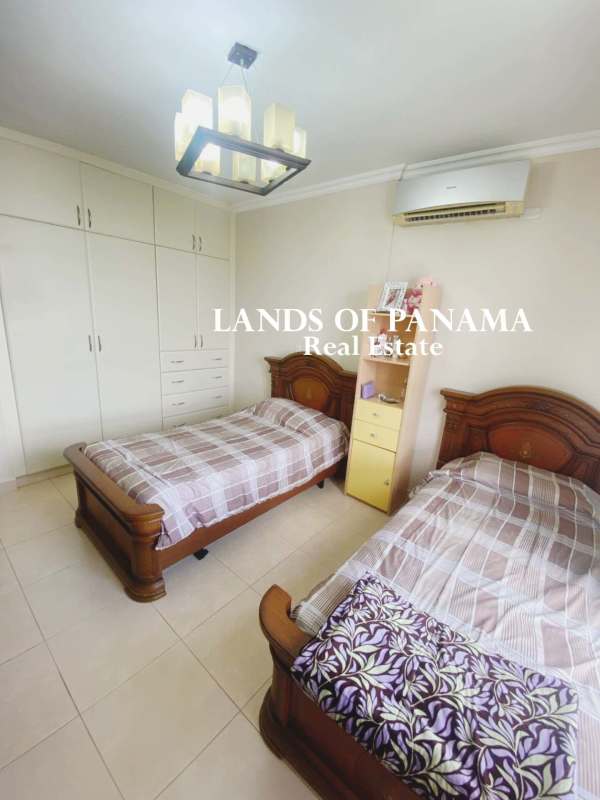 Modern living room with sectional red couch, tiled floors and large windows with skyline views in Costa del Este Panama