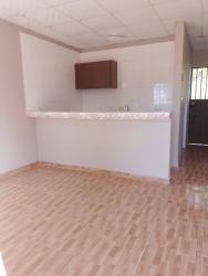 Minimalist kitchen with wood-look tile floor and breakfast counter in Santiago apartment
