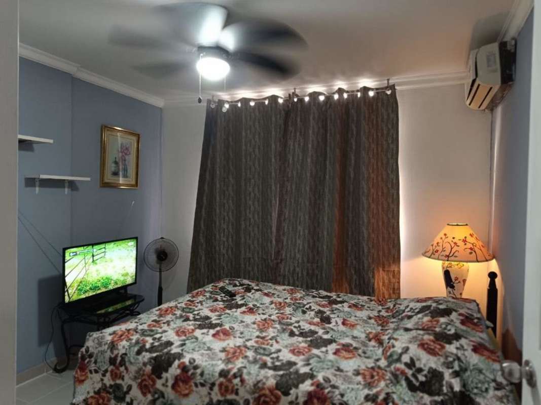 Bedroom with floral bedcover, AC unit, TV, and shelves at PH Mystic Park Panama City