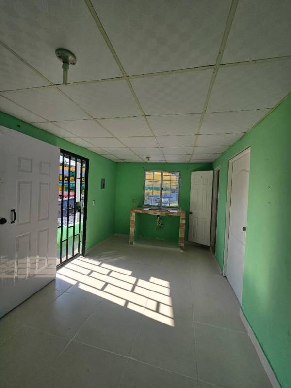 Compact bathroom with ceramic tiles wall, toilet, sink, window light in affordable Panama rental