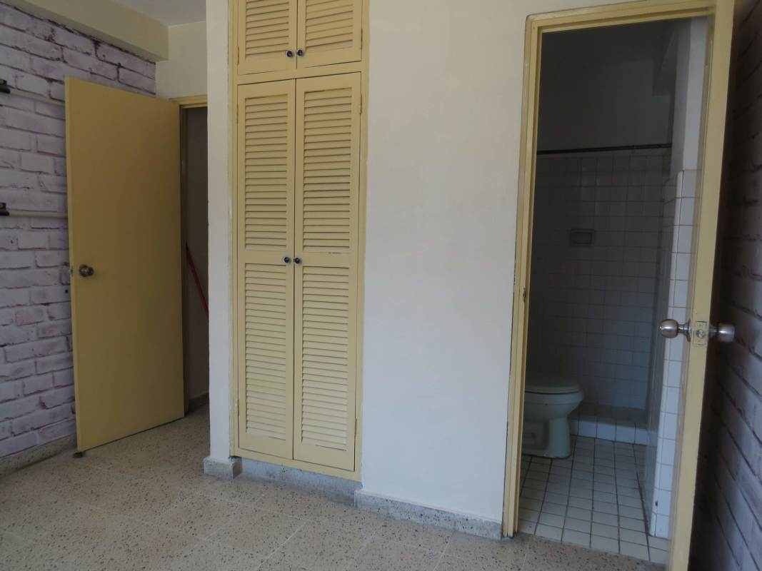 Bedroom with attached bathroom, built-in closet, brick wallpaper in PH Comercial El Carmen Panama City