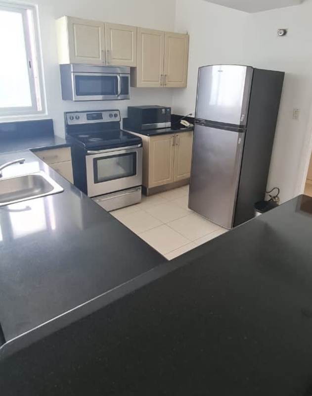 Contemporary kitchen with appliances, black countertops, beige cabinets in PH Miramar Panama