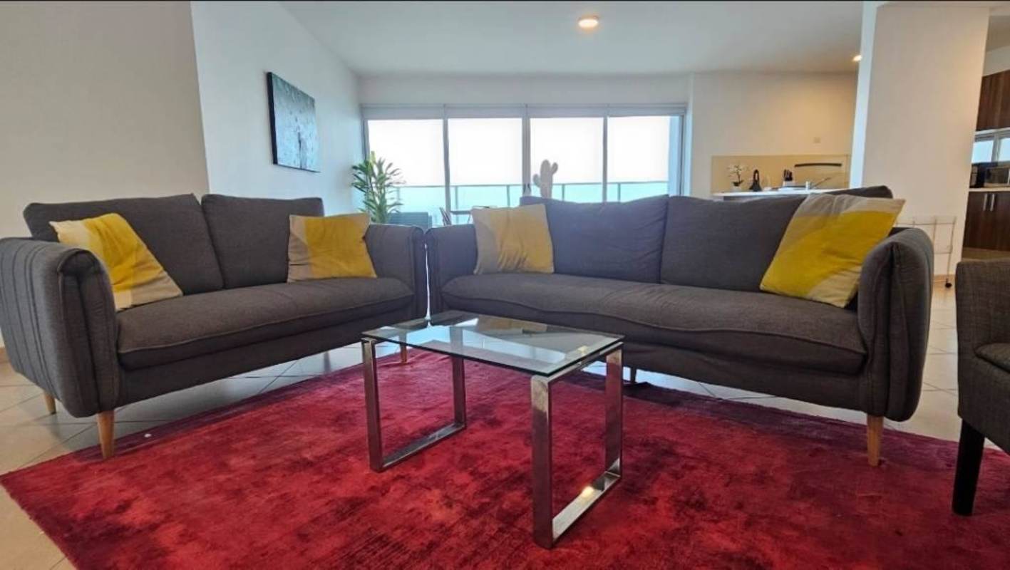 Bedroom with glass doors to ocean view balcony, white bedding, wooden furniture at Oasis on the Bay