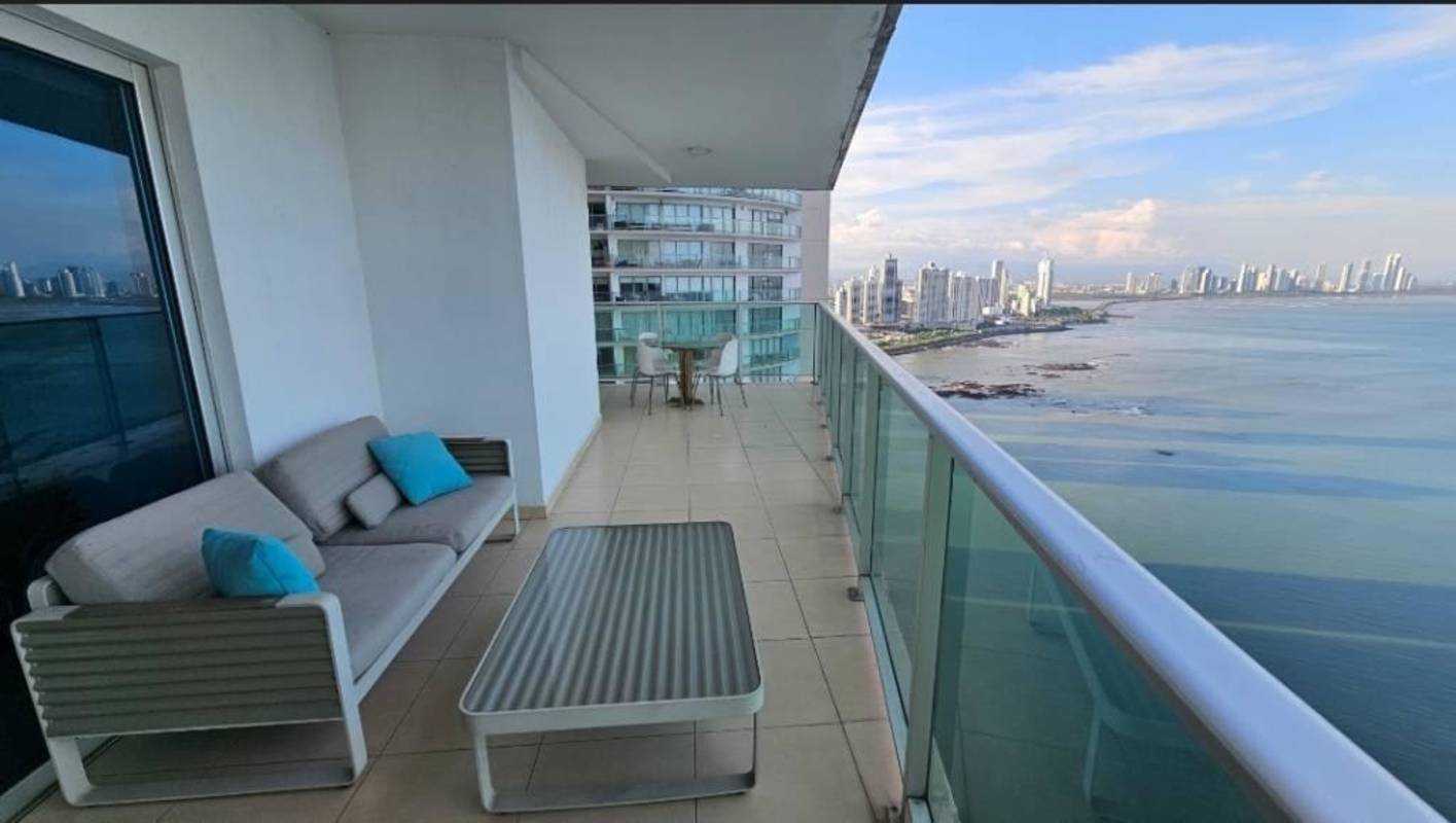Dining area with ocean views, large windows, red mesh chairs and peacock wall art at Oasis on the Bay Panama