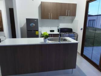 Modern kitchen with wood cabinets, island sink, refrigerator and sliding glass doors Senderos Santa Monica Panama