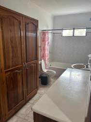 Traditional bathroom with double sink vanity, large wooden cabinets and bathtub for rent in Villa Mercedes David