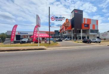 Exterior multi-story commercial plaza with auto dealership frontage and large billboards near Chorrera Panama