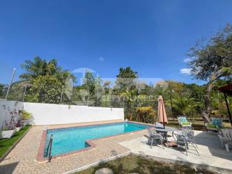 Private swimming pool with patio umbrellas, outdoor seating, lush landscaping at Playa Gorgona beach house
