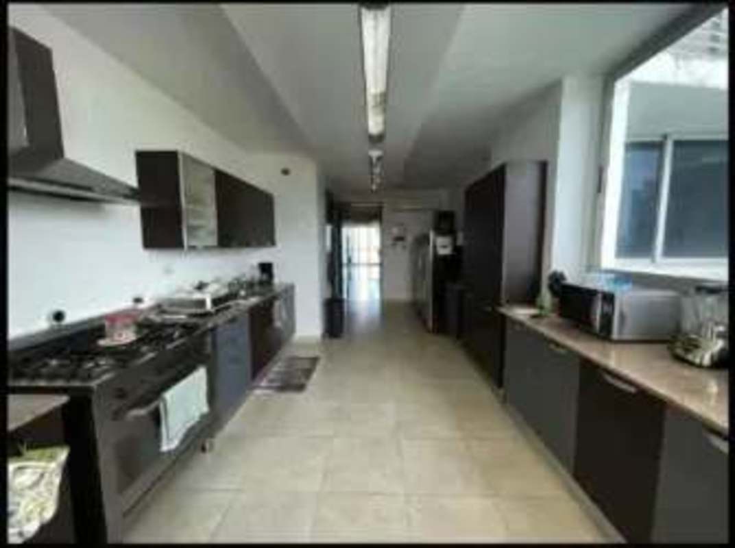 Modern galley kitchen with stainless steel appliances and dark cabinets at Pearl at the Sea Panama
