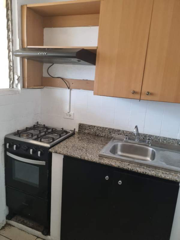Compact kitchen with granite counter, gas stove, wooden cabinets near Multiplaza Panama