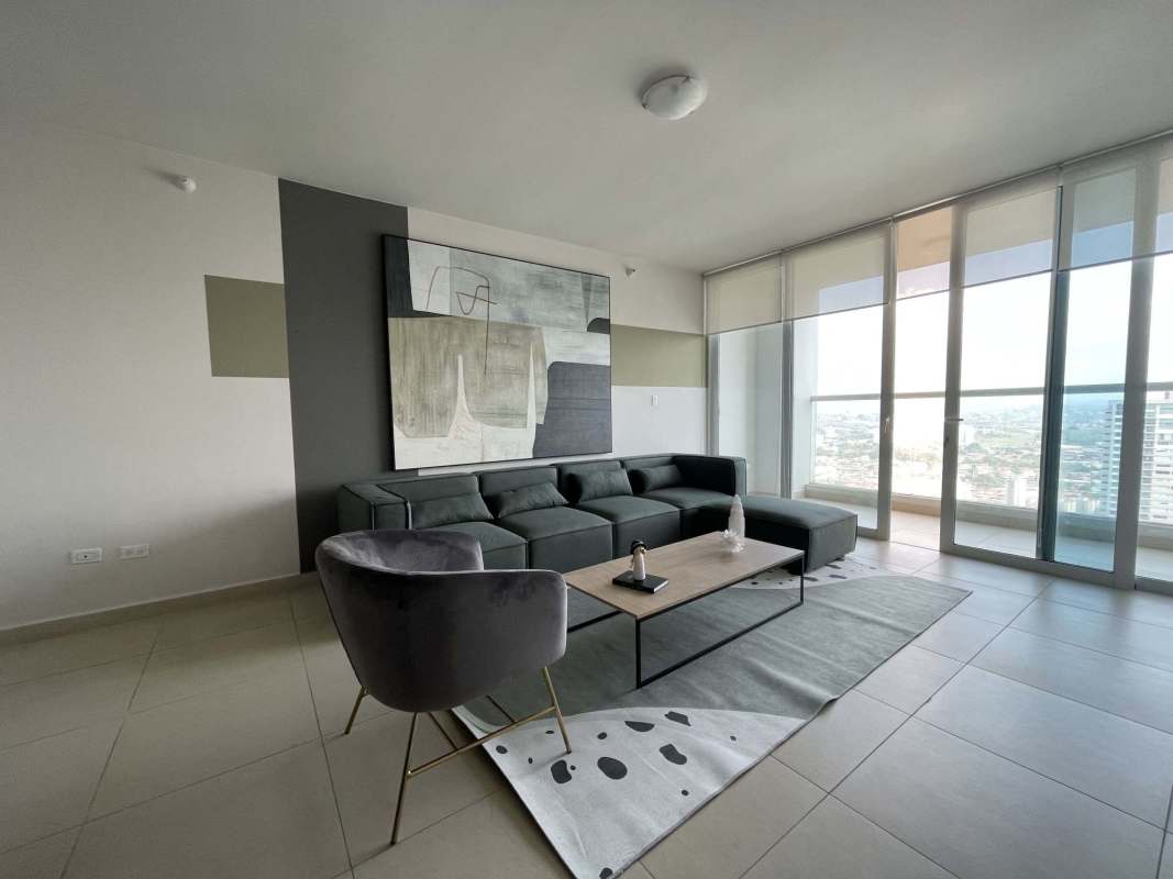 Bright living room with grey sofa, accent chair, and floor-to-ceiling windows in Costa del Este Panama