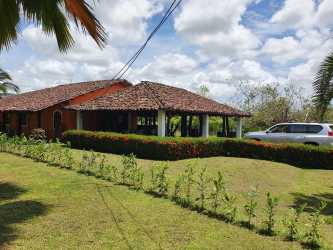 Yellow house clay tile roof covered porch landscaped garden Equus Village Pedasí