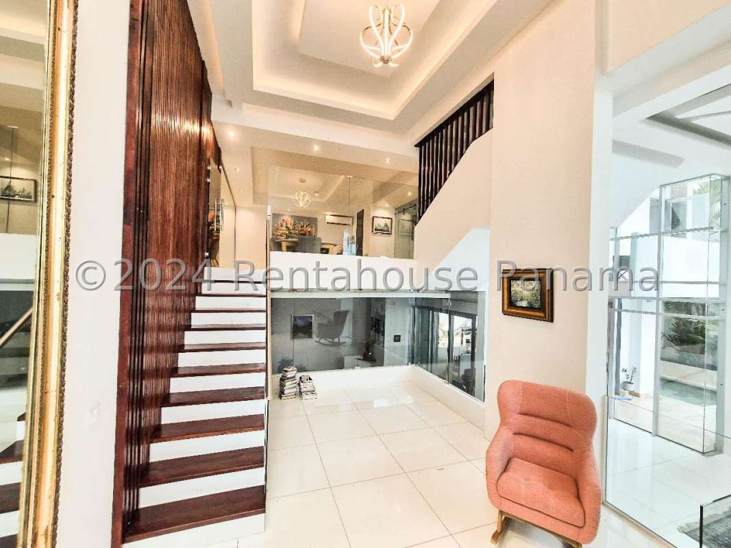 Spacious open plan living area with glass staircase, wood accents PH Minimal Houses Altos del Golf Panama