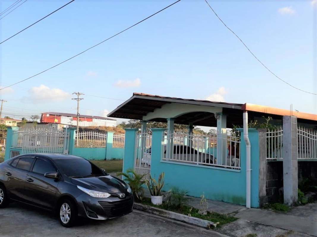 Residential suburban street view of blue gated house with carport and fence in Panama City