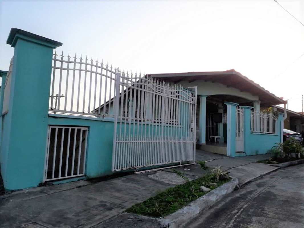 Gated exterior with blue walls, metal fence, covered carport, plants in Las Cumbres Panama
