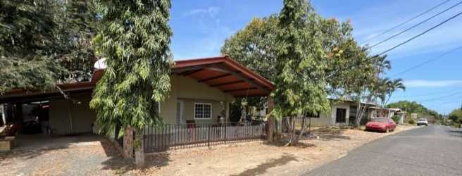 Patio with red roof trim, fence, carport, mature trees in front yard Guararé District Panama