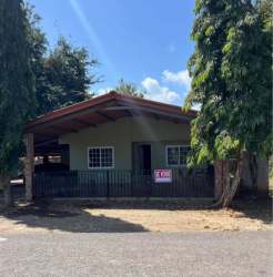 Beige single-story house with front porch, fenced yard, trees surrounding on sunny day Guararé Panama