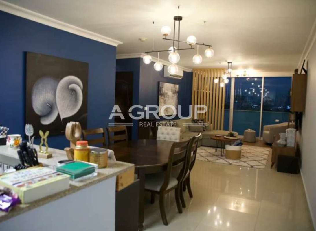 Modern living room with large windows, wood floor, wall-mounted TV PH Pacific Sun Punta Pacifica