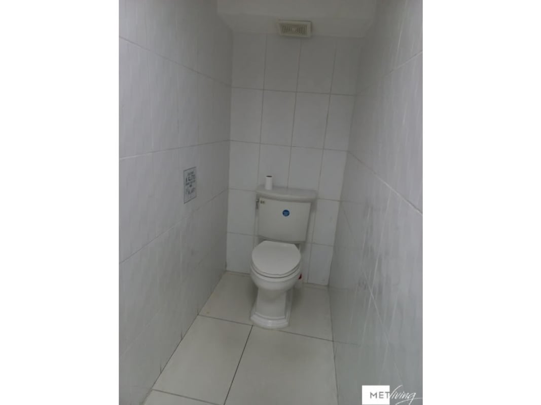 Compact white tiled bathroom with flush toilet inside modern office in Panama