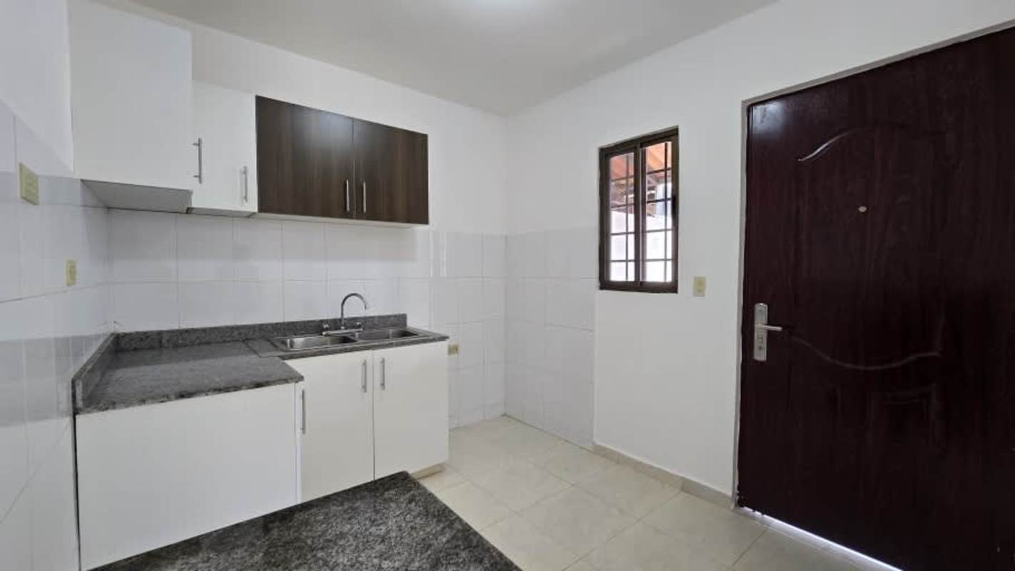 Exterior photo of two-level white house with large fenced yard in Las Cumbres Panama