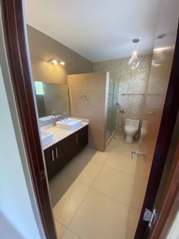 Bathroom with double sinks, glass enclosed shower and modern finishes in Panama Pacifico house