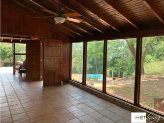 Sunroom with wood panel walls large windows overlooking forest Cerro Azul