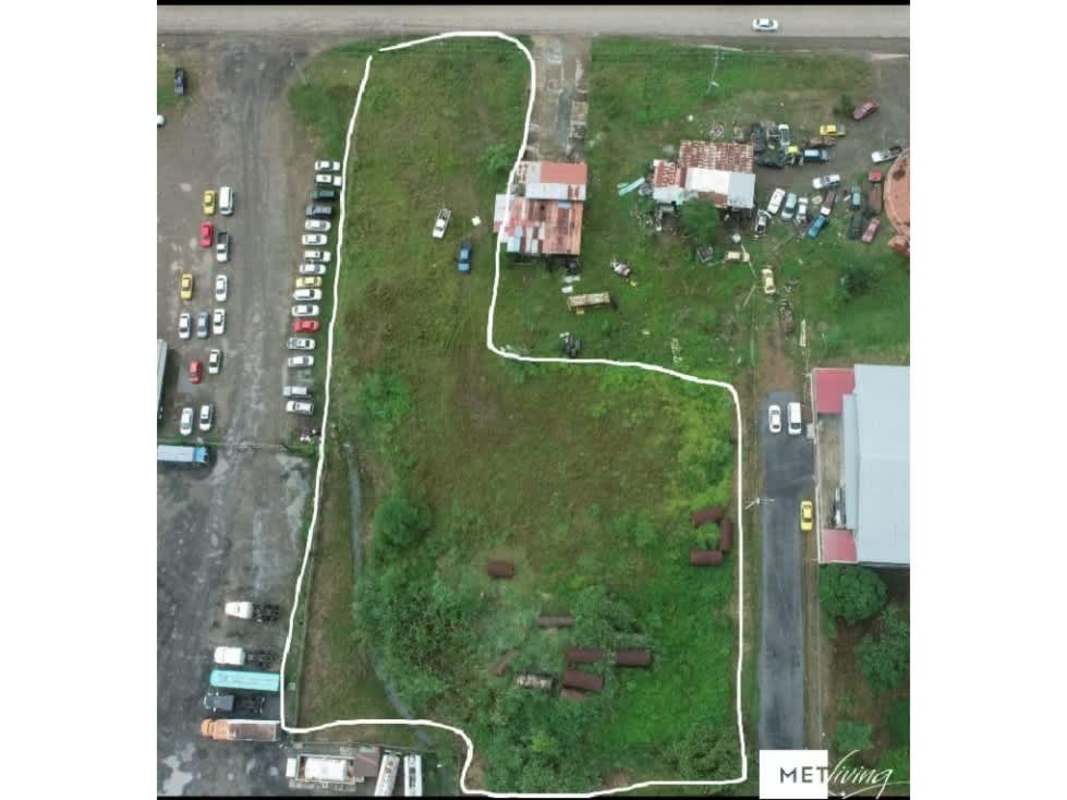 Vacant industrial lot Tanara Chepo with roadway frontage, vehicles, fencing, smaller structures