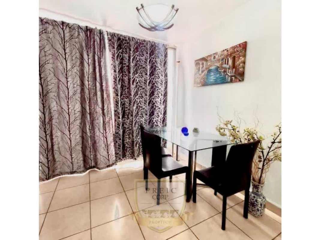 Contemporary dining area with glass table, black chairs near balcony in Brisas de España furnished apartment Carrasquilla