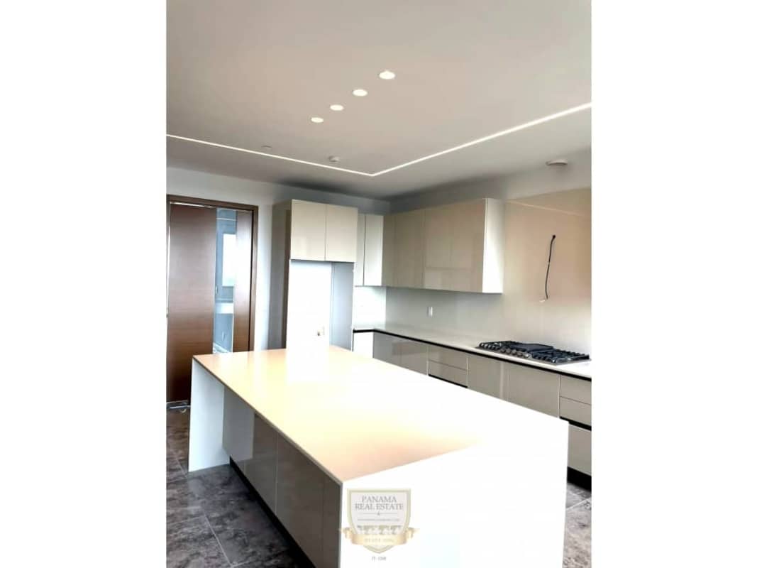 Modern kitchen with large marble island and open dining area in Santa María golf club community