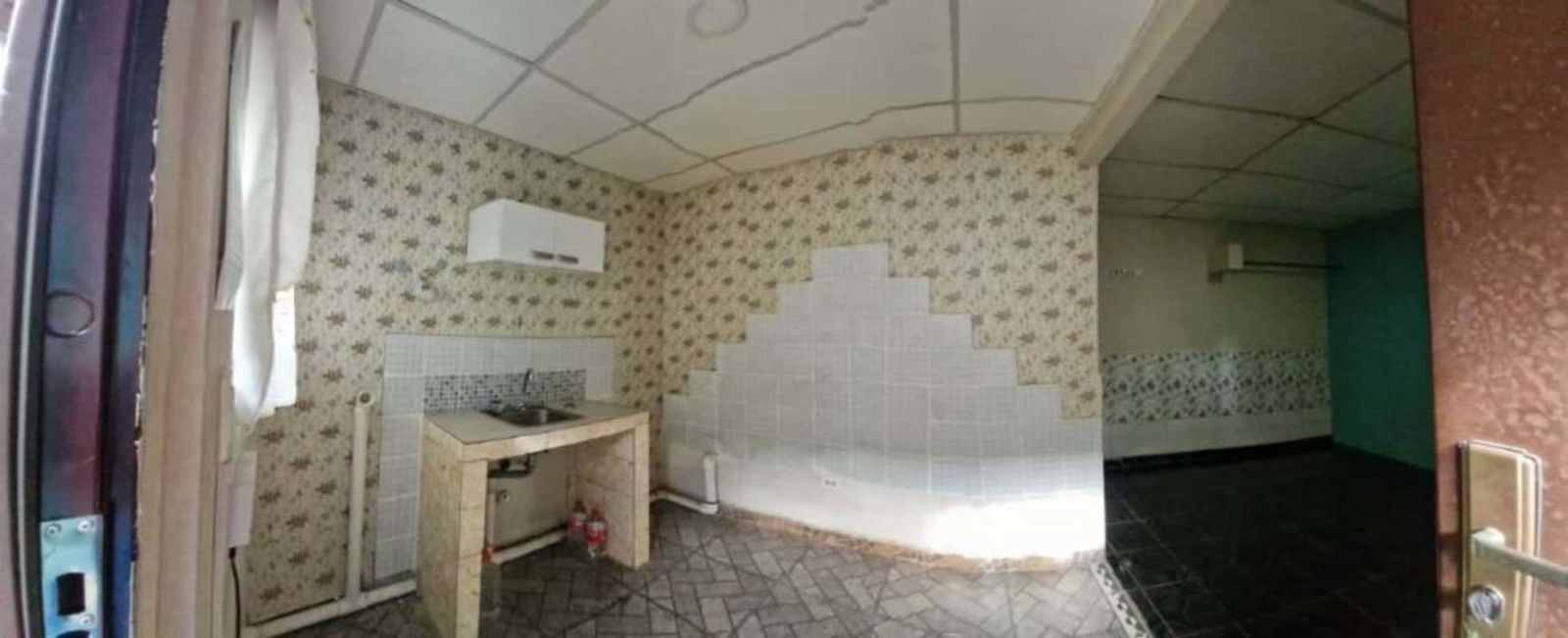 Small kitchenette with tiled counter and vintage wallpaper in affordable room in Tocumen