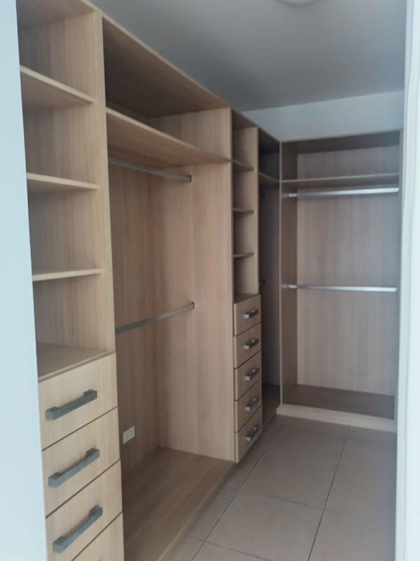 Walk-in closet with built-in wood cabinetry and shelving at BICSA Tower apartment Panama City
