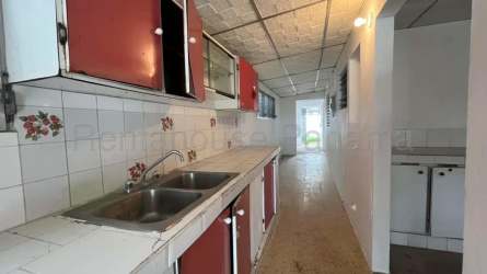 Narrow galley kitchen with decorative tiles, double sink and red cabinets Panama house for sale
