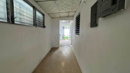 Simple interior hallway with tiled floor and louvered windows inside La Chorrera house
