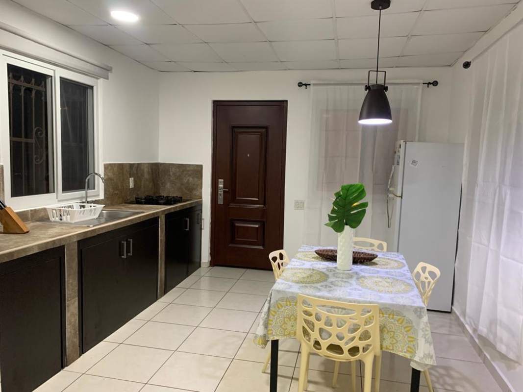 Compact kitchen with stove and fridge, dining area, window with bars in Villa Lucre Panama