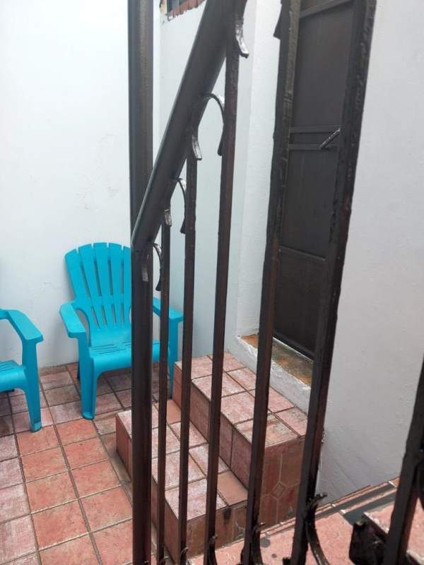 Private enclosed patio with wrought iron railing and blue plastic chairs in Villa Lucre Panama