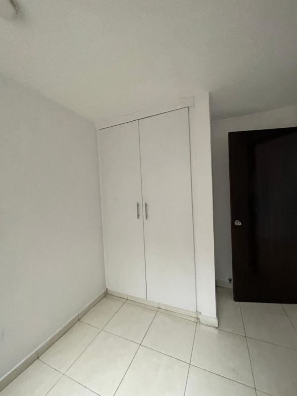 Minimalist bedroom with large window, white walls, and wardrobe Panama apartment