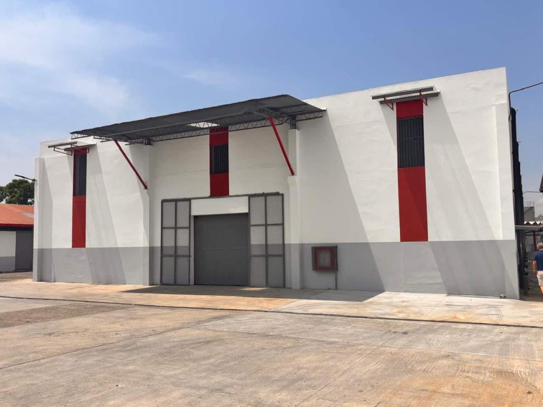 Exterior of warehouse with large metal industrial entrance, ventilation grilles, and canopy