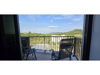 Private balcony with outdoor seating overlooking green landscape and city in PH Céntriqo Panama