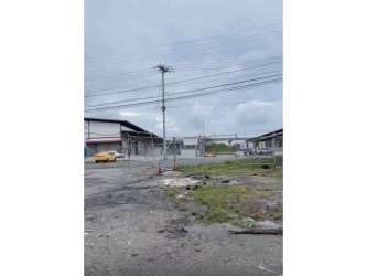 Industrial buildings with utility poles adjacent to fenced gravel commercial lot in Panama City