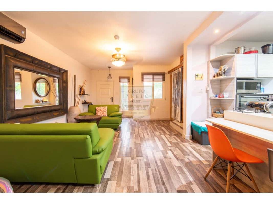 Open plan living area with green sofas and art accents in Brisas del Golf Panama house for sale