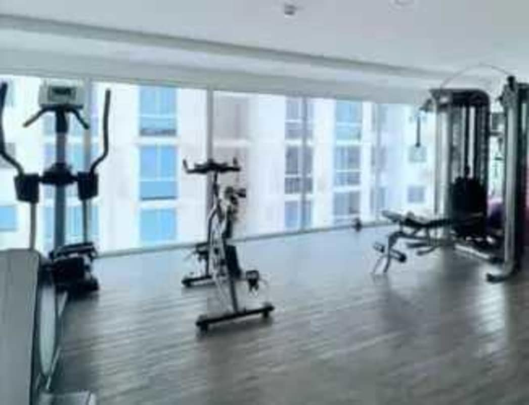 Modern gym with machines and city view at PH Vía España in Panama City for residents use