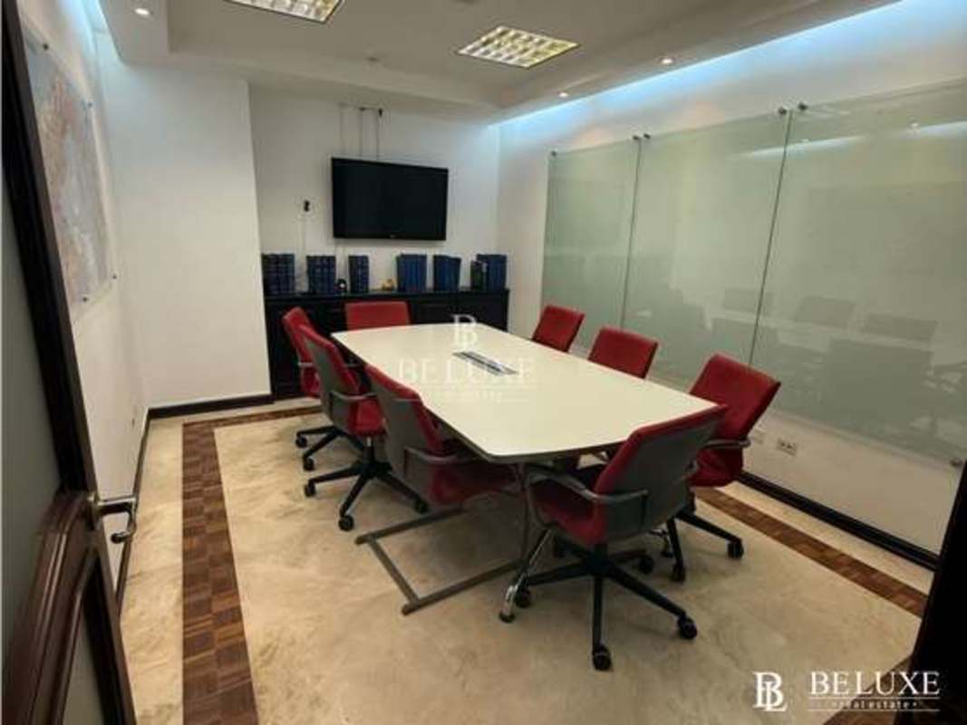 Modern conference room with large table, red chairs and wall-mounted TV in Torre Banesco Panama City