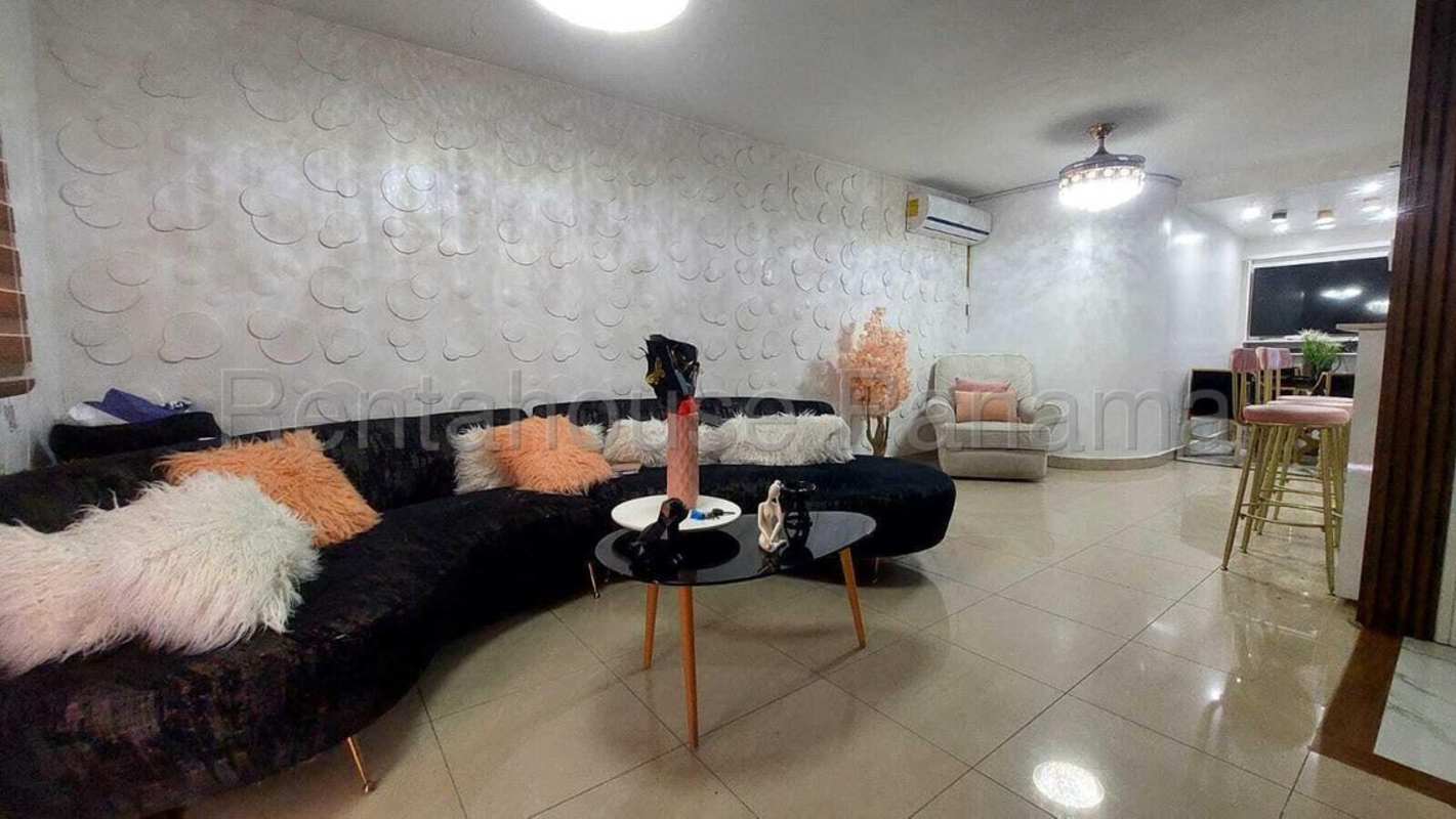 Bright living room with black sofa, accent wall and dining area in Condado del Rey, Panama City