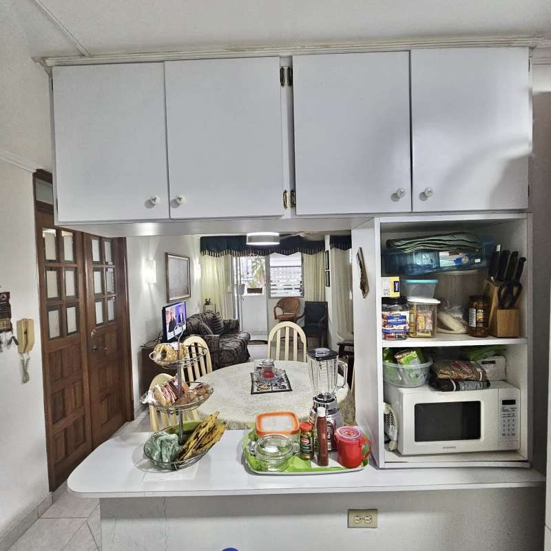 Traditional kitchen with white cabinets, microwave, and open shelving in PH Brisas de España Panama City
