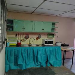 Compact kitchenette with fridge, wooden shelf, appliances and kitchen essentials in Veraguas student shared home